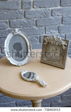 Old picture frames, lying mirror on the table with grey brick wall background remote view