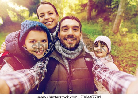 travel, tourism, hike and people concept - happy family with backpacks taking selfie and hiking