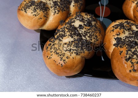 Buns with poppy seeds on a black plate and blue napkin.
