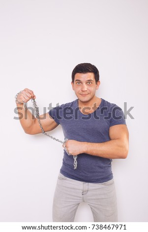 young athletic man showing his muscles. uses iron chain. emotional portrait. street style: jeans and a colored t-shirt. clear skin and short hair