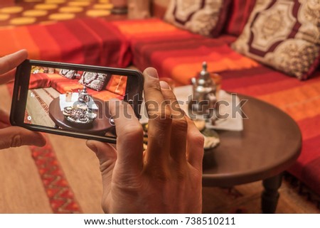 A  young man taking a picture with his smart phone of a traditional tea serving in Morocco. 