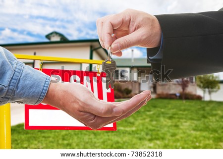 A  realtor handing over keys to a buyer in-front of a house