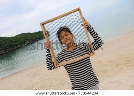 Asian girls having fun with a steel mesh wooden frame on the beach.