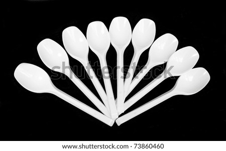 Disposable white plastic spoons, isolated on black background