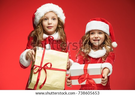 Two happy girls in santa claus hats with gift boxes at studio
