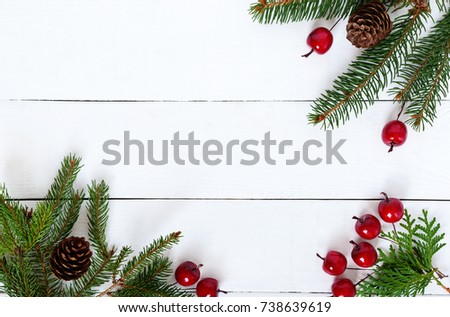New Year's, Christmas theme. Green fir branches with cones, decorative berries on white wooden background. Celebratory background. Free space for inscriptions, notes.