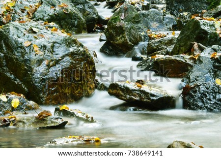 Beautiful photo of river with soft flowing water and large colored rocks, wild in autumn, landscape nature