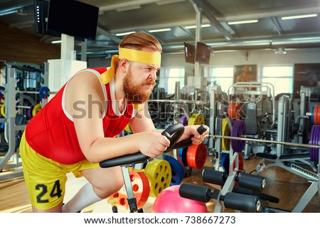 A fat man on a bike simulator in the gym