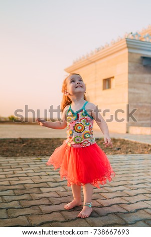 the little girl in a red skirt against the background of a decline