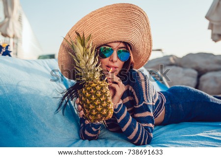 Beautiful woman in a hat and sunglasses lies on a beach chaise.