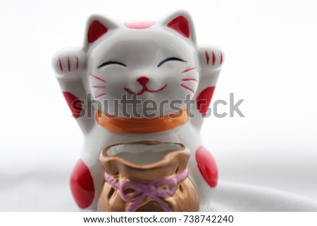 Close up Cute funny happy Chinese lucky cat with money bag on white curtain background 