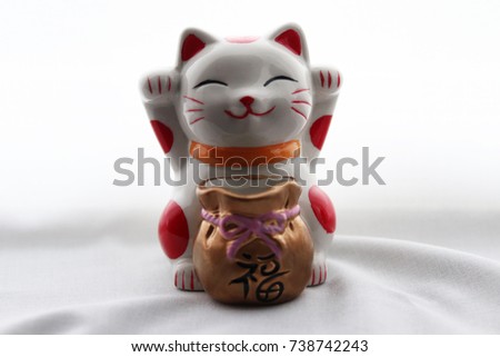 Horizontal view Cute funny happy Chinese lucky cat with money bag on white curtain background 