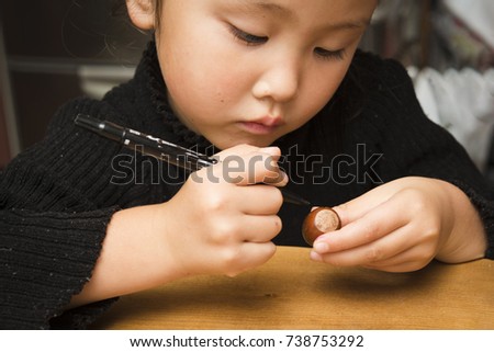 Little girl drawing face on acorn