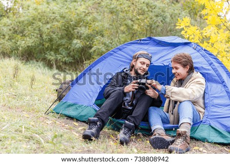 A young couple of tourists in the forest watching photos on the camera.
