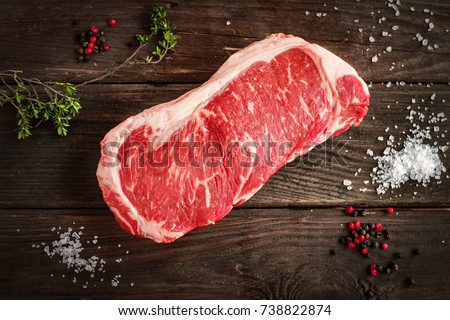 raw strip loin steak on white wooden background in rustic style with salt and herbs Royalty-Free Stock Photo #738822874