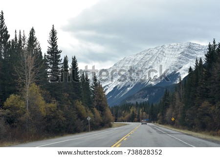 Lone car on a Canadian highway through the snow capped Rocky Mountains