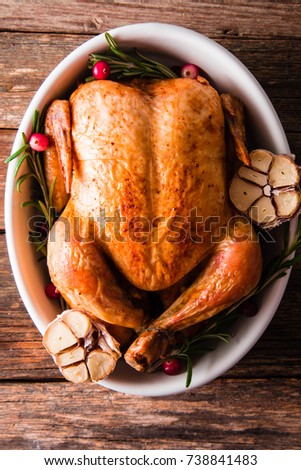 Roasted chicken with cranberries, rosemary and garlic  on wooden table, top view.