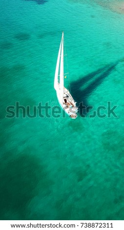 Aerial drone, bird's eye view of yacht cruising near tropical island with turquoise and sapphire sea