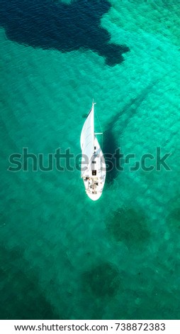 Aerial drone, bird's eye view of yacht cruising near tropical island with turquoise and sapphire sea