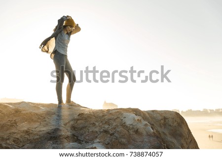 Beautiful woman with a yellow cap on a cliff over the beach