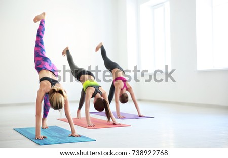 Group of young women practicing yoga in light room
