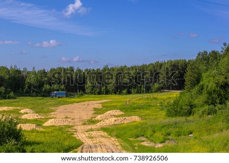 Summer landscape blue sky with clouds green grass and country road in forest