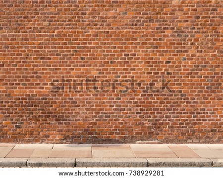Red brick wall with sidewalk