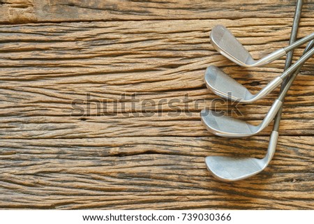 Old golf clubs on rough wooden surface top view with copy space