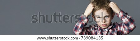 annoyed young boy with freckles scratching his hair for head lice or allergies, grey long panorama
