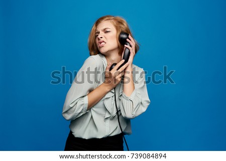 emotion, young woman with trumpet phone on blue background studio                               