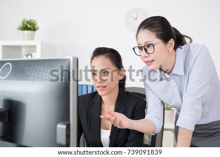 project manager teaches her subordinate how to working on new online shopping project for their client on the computer.