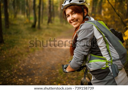Photo of woman wearing helmet on bicycle in autumn forest