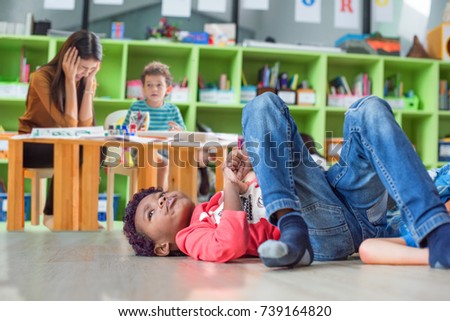 naughty preschool does not pay attention to the class with upset and disappointed dizziness of the teacher in background