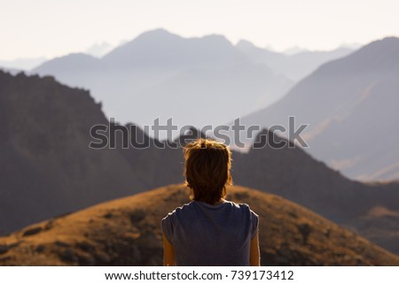 One person looking at view high up on the Alps. Expasive landscape, idyllic view at sunset. Rear view. Royalty-Free Stock Photo #739173412