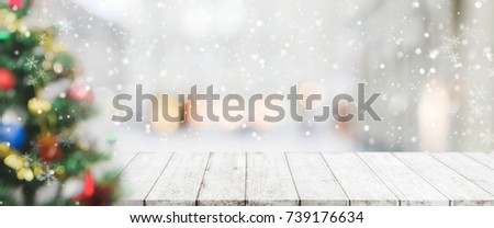 Wood table top on blur with bokeh christmas tree background with snowfall - can be used for display or montage your products.