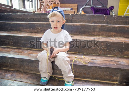 the child plays with headphones, listening to music from your phone. sitting in a room on the stairs