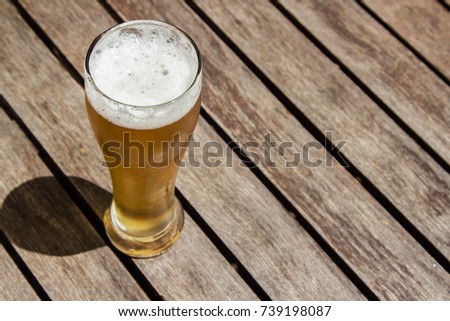 A golden craft beer (lager) on a wooden table top. 