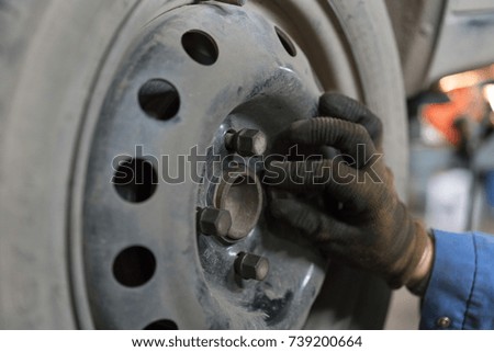 The mechanic twists the nuts on the wheel