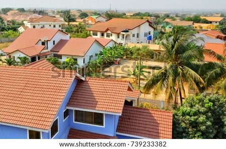Residential area in West Africa. Top view on family houses, yards with gardens, surrounded by fences and roads. Modern lifestyle in developing countries. 