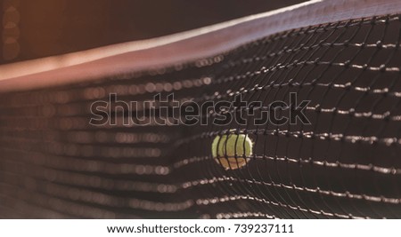 Close-up of tennis ball striking a net of tennis court outdoors, sunny weather