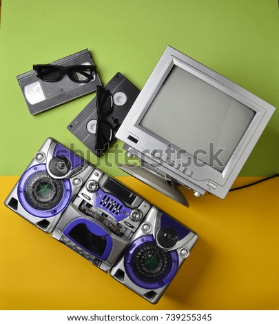 Retro media technologies. Entertainment 80s. Black white lamp TV, tape recorder, video cassette, 3d glasses on a green pastel yellow background. Top view. Flat lay.