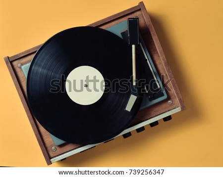 Vintage vinyl turntable with vinyl plate on a yellow pastel background. Entertainment 70s. Listen to music. Top view. Royalty-Free Stock Photo #739256347