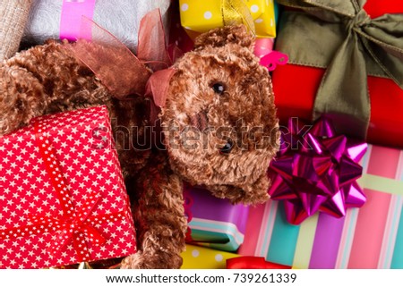 Close up on a Teddy bear laying among gifts. Presents under a fir tree. Christmas fairytale.
