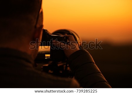 DSLR Videography and Photography Concept. Modern Digital Camera with Telephoto Lens. Photographer at Work During Scenic Sunset.