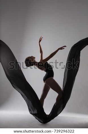 Silhouette of a ballerina dancing on a black cloth. Studio photography. The concept of beauty and grace.