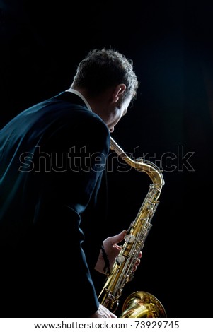 A jazz saxophone player facing the audience as he plays Royalty-Free Stock Photo #73929745