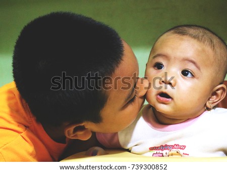 A brother kisses his baby sister