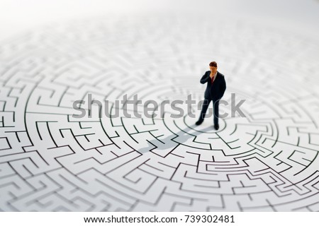 Miniature people: Businessman standing on center of maze. Concepts of finding a solution, problem solving and challenge.
 Royalty-Free Stock Photo #739302481