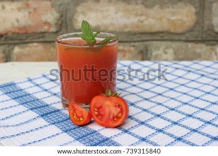 Glass of freshly squeezed tomato juice on towel background