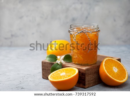 orange jam in a glass jar, fresh oranges on a gray concrete background Royalty-Free Stock Photo #739317592